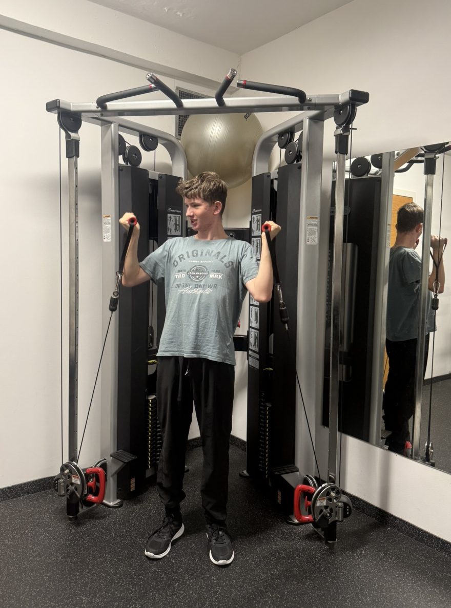klient posiluje ruce na stroji v posilovně na na fitness víkendu