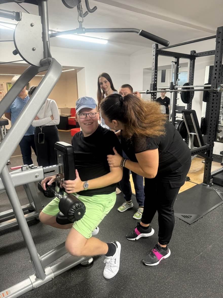 asistentka chválí klienta při cvičení v posilovně na fitness víkendu